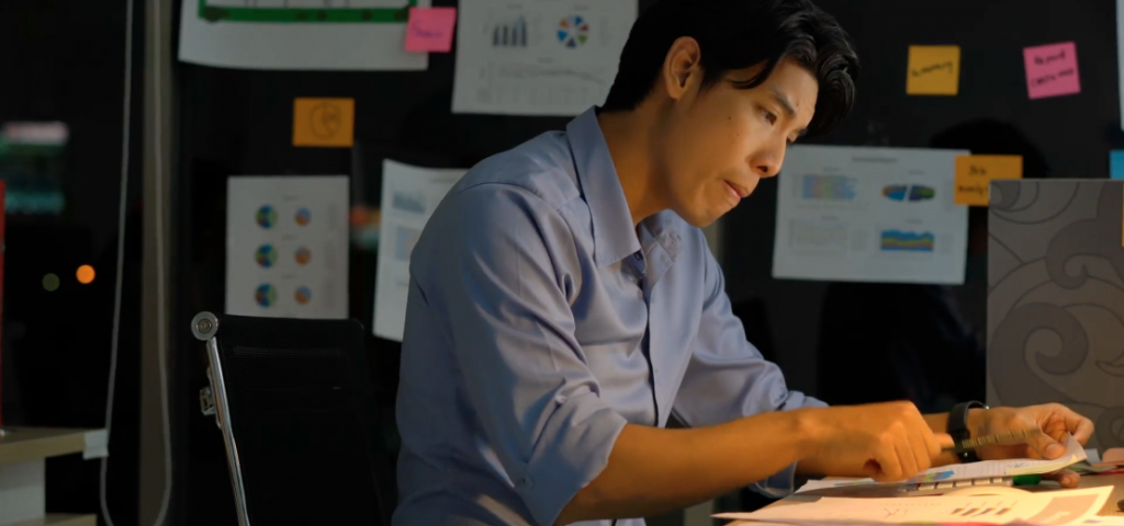 A man sitting at his desk working on a laptop.